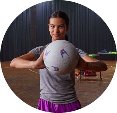 Young person holding a netball ball facing the camera