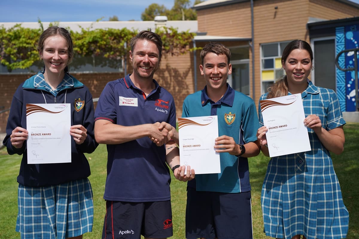 Young people in school uniform holding certificates