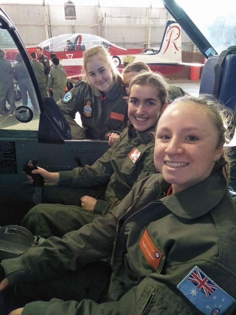 Young people sitting in a plan in army uniform smiling