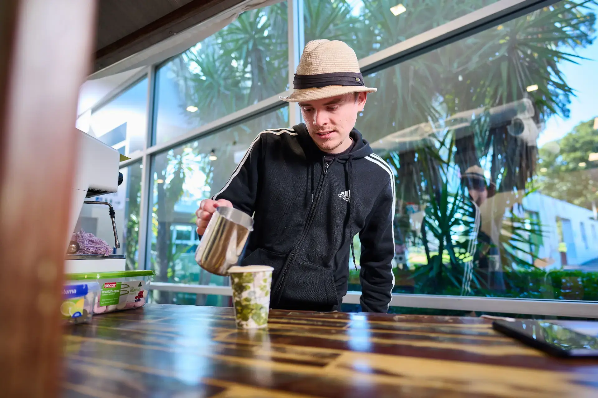 Barista pouring hot milk into coffee